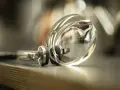 Szkła progresywne Hoya cennik: soczewka okularowa z metalową oprawką leży na książce.