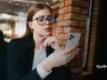 Kobieta w okularach z niebieskimi filtrami przegląda telefon. Różne rodzaje okularów mogą chronić wzrok.