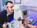 Badanie wzroku z użyciem perymetrii kinetycznej. Pacjent patrzy w urządzenie, technik obsługuje sprzęt.