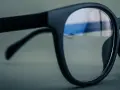 Czarne okulary z soczewkami z powłoką antyrefleksyjną. W odbiciu widać niebieskie światło, sugerujące antyrefleks zielony czy niebieski.