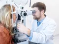 Optyk bada wzrok pacjentki przy użyciu specjalistycznego sprzętu.