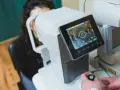 Badanie wzroku za pomocą urządzenia angio OCT. Pacjentka patrzy w aparat, a technik obsługuje sprzęt.