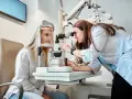 Prywatny okulista bada wzrok pacjentki, przygotowując receptę na okulary.