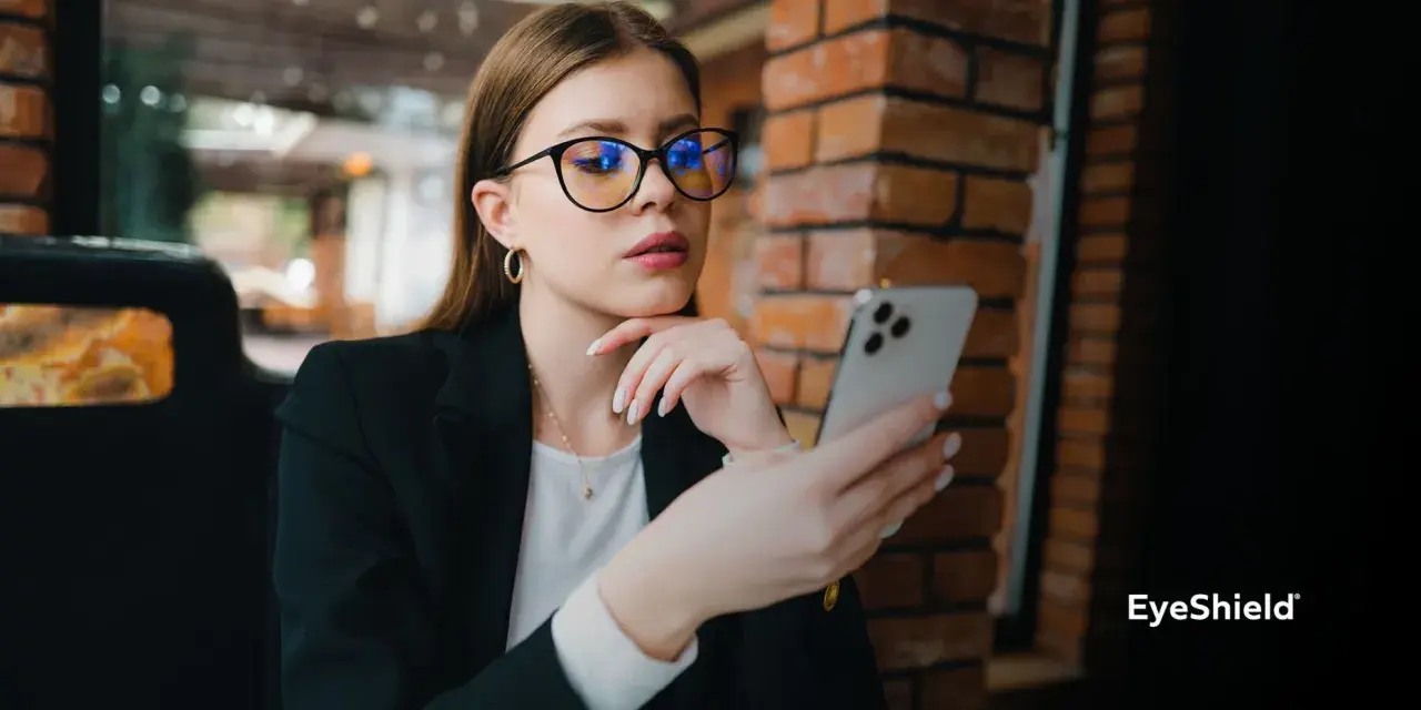 Kobieta w okularach z niebieskimi filtrami przegląda telefon. Różne rodzaje okularów mogą chronić wzrok.
