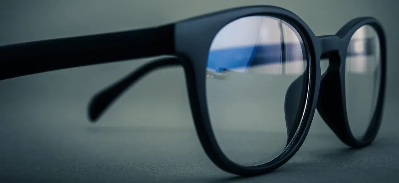 Czarne okulary z soczewkami z powłoką antyrefleksyjną. W odbiciu widać niebieskie światło, sugerujące antyrefleks zielony czy niebieski.