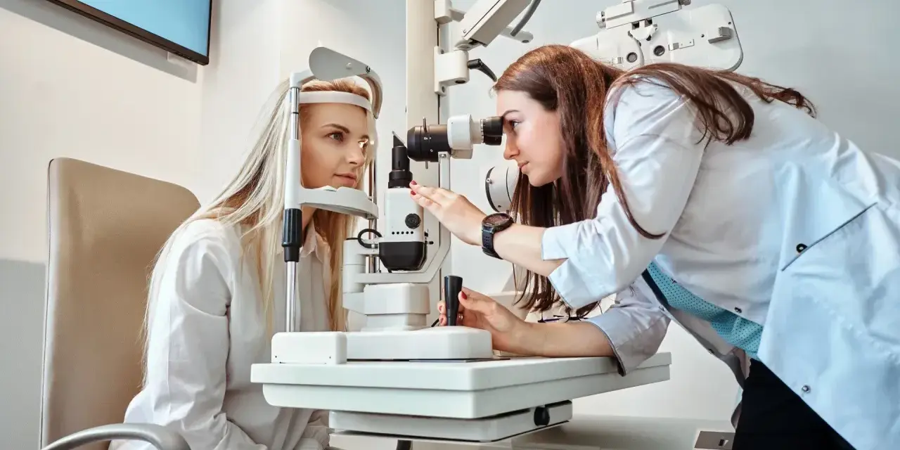 Prywatny okulista bada wzrok pacjentki, przygotowując receptę na okulary.