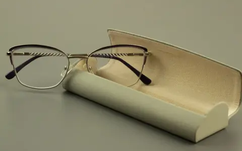 Eleganckie okulary z fioletowymi oprawkami i szkłami sferycznymi, obok futerału.