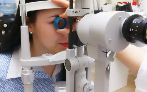 Kobieta podczas badania dna oka przy użyciu specjalistycznego sprzętu. Okulista dokładnie sprawdza wzrok pacjentki.