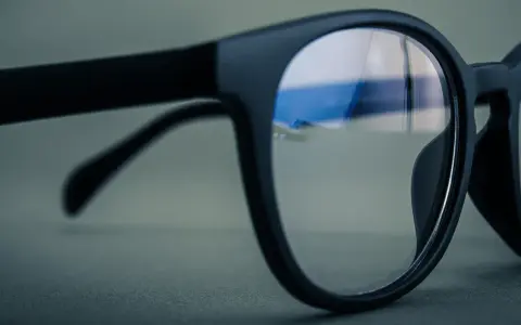 Czarne okulary z soczewkami z powłoką antyrefleksyjną. W odbiciu widać niebieskie światło, sugerujące antyrefleks zielony czy niebieski.