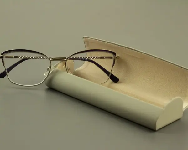 Eleganckie okulary z fioletowymi oprawkami i szkłami sferycznymi, obok futerału.