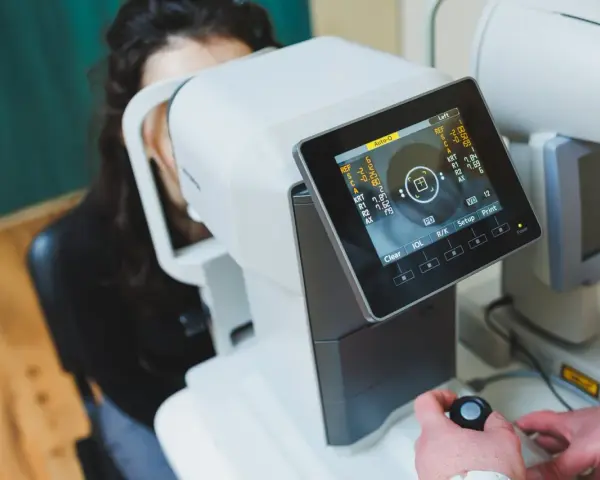 Badanie wzroku za pomocą urządzenia angio OCT. Pacjentka patrzy w aparat, a technik obsługuje sprzęt.