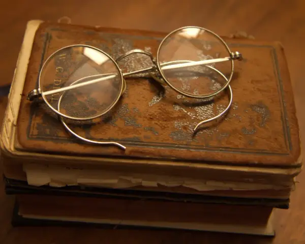 Okulary na starym oprawionym tomie, przypominające czasy, kiedy wynaleziono okulary, by czytać.