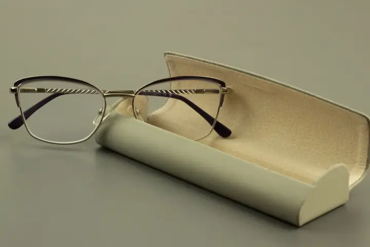 Eleganckie okulary z fioletowymi oprawkami i szkłami sferycznymi, obok futerału.
