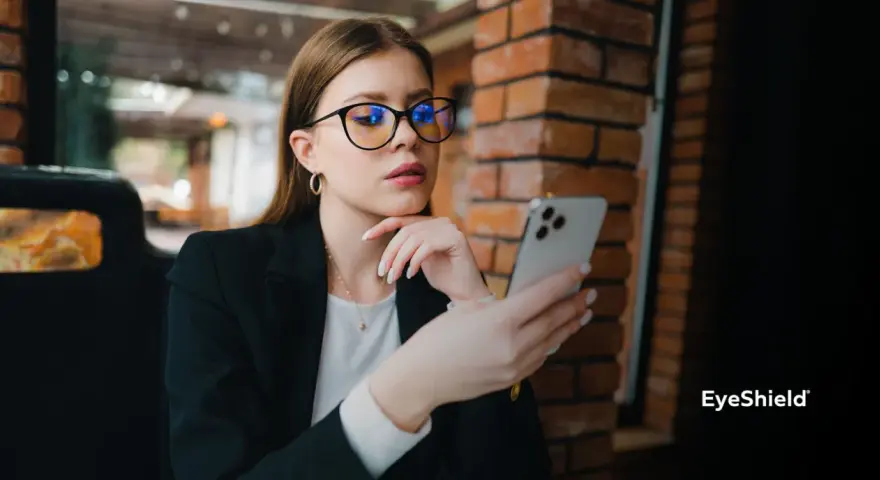 Kobieta w okularach z niebieskimi filtrami przegląda telefon. Różne rodzaje okularów mogą chronić wzrok.