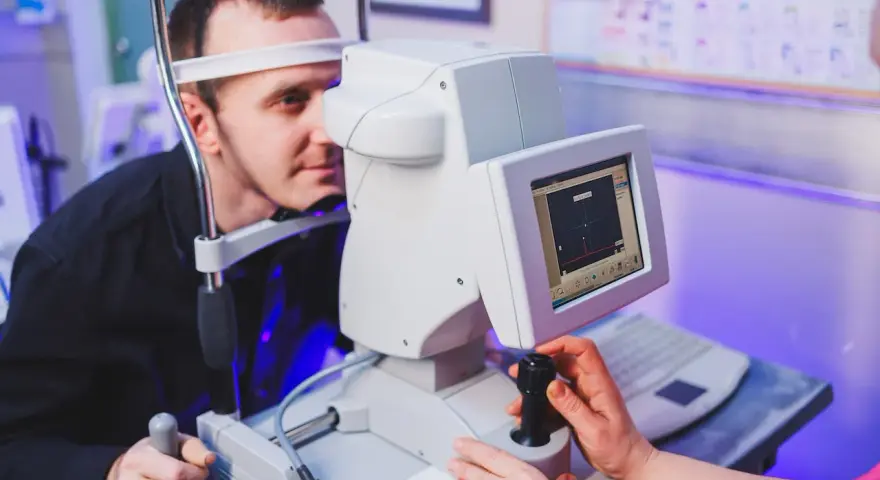 Badanie wzroku z użyciem perymetrii kinetycznej. Pacjent patrzy w urządzenie, technik obsługuje sprzęt.