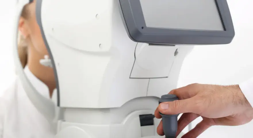 Badanie wzroku pacjentki przy użyciu nowoczesnego sprzętu. Lekarz manipuluje joystickiem, jakby sterował statkiem kosmicznym, a pacjentka patrzy w dal, jakby widziała kolorowy balon.