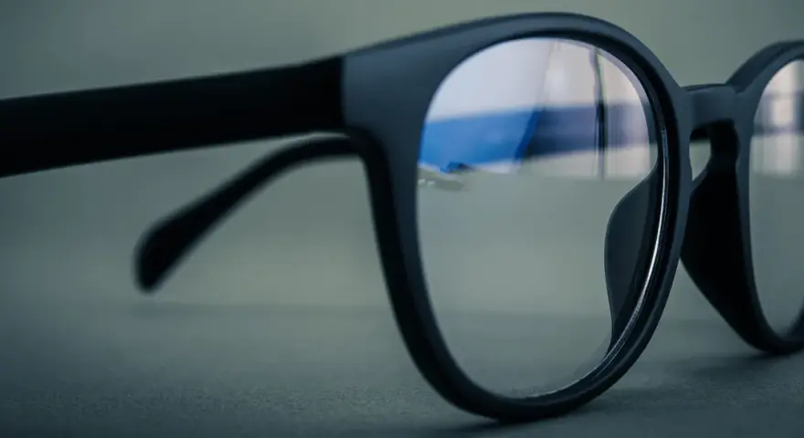 Czarne okulary z soczewkami z powłoką antyrefleksyjną. W odbiciu widać niebieskie światło, sugerujące antyrefleks zielony czy niebieski.