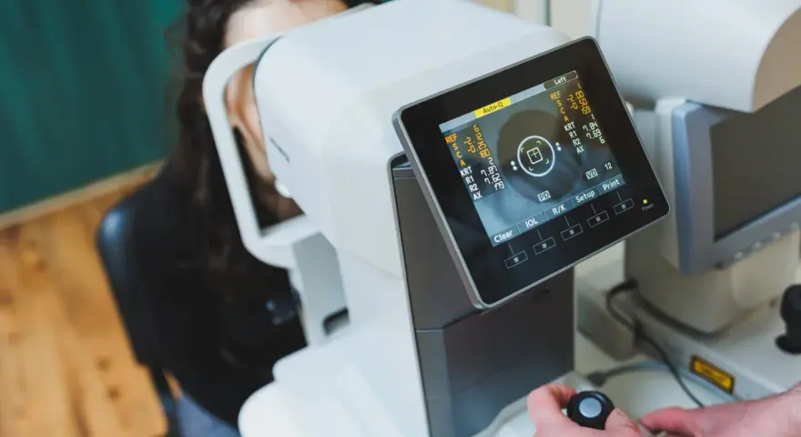 Badanie wzroku za pomocą urządzenia angio OCT. Pacjentka patrzy w aparat, a technik obsługuje sprzęt.