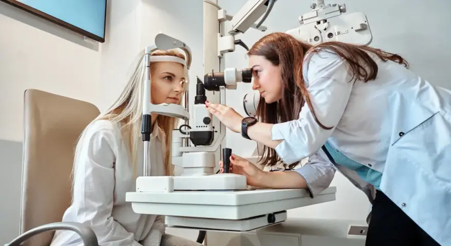 Prywatny okulista bada wzrok pacjentki, przygotowując receptę na okulary.