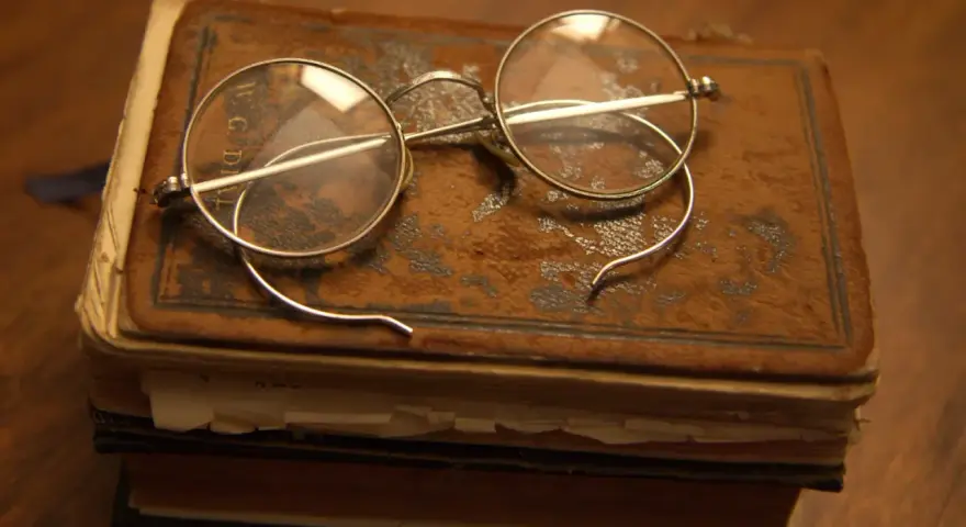 Okulary na starym oprawionym tomie, przypominające czasy, kiedy wynaleziono okulary, by czytać.