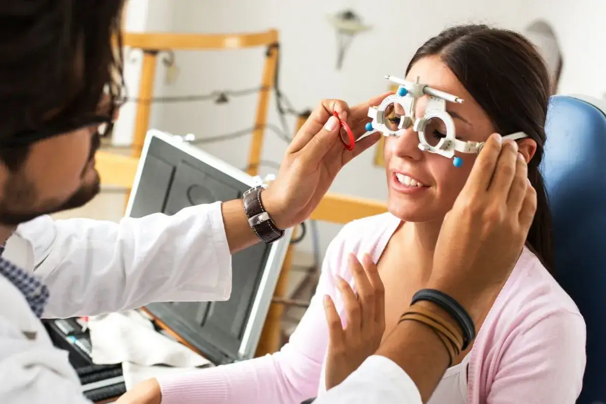 Optometrysta bada wzrok pacjentki, która ma założony próbny aparat do korekcji wzroku.